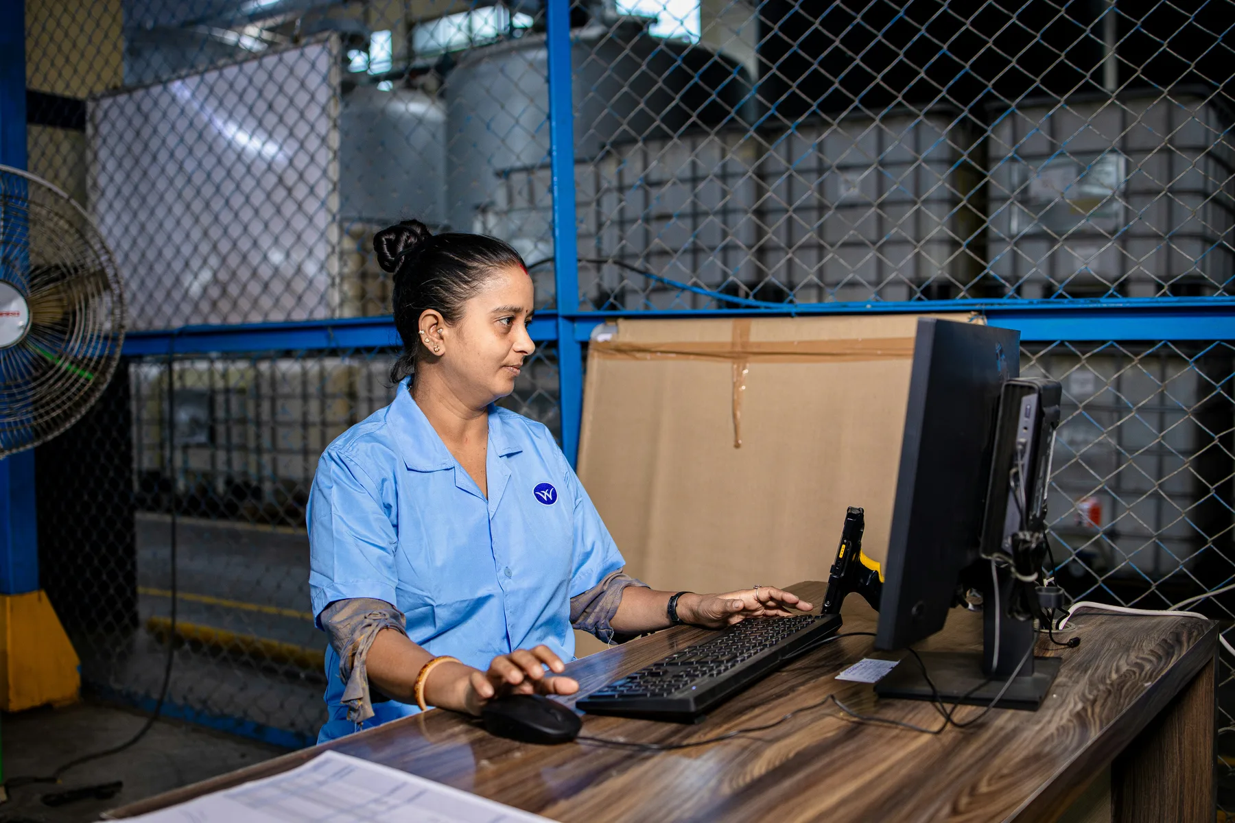 Warehouse worker processing orders on computer, representing automated ERP order entry
